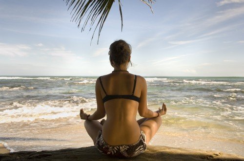 mujer haciendo yoga en la playa