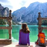 mochilera con su mochila a orillas de un lago en los Dolomitas, Italia