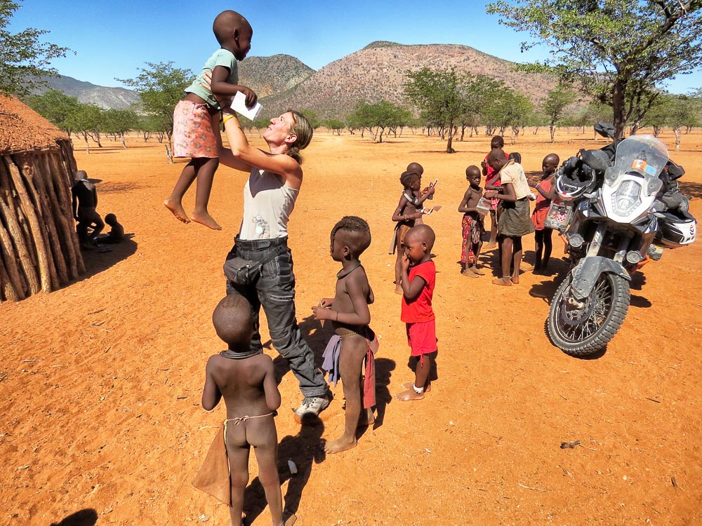Almudena Teulón con varios niños africanos al dar la vuelta al mundo en moto