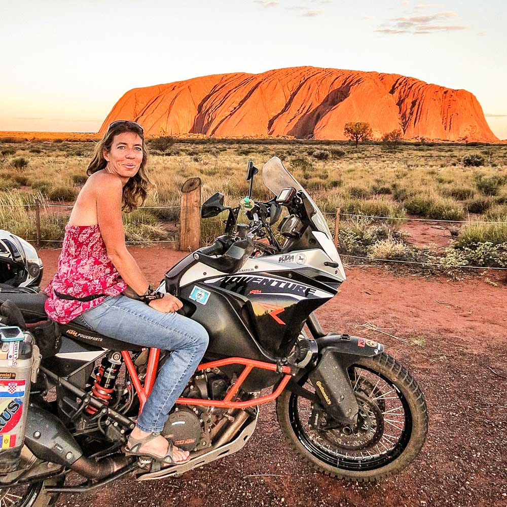 Almudena Teulón junto con su moto en el Monte Uluru, Australia