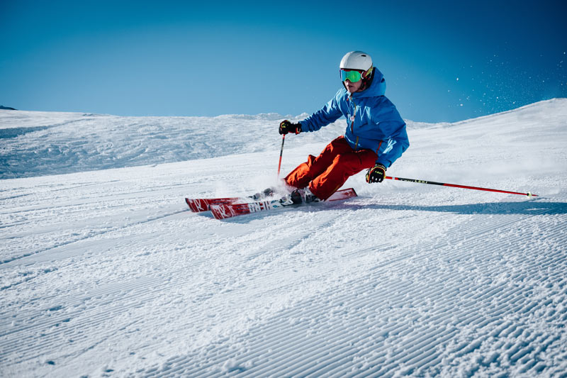 Viajes de Esquí, esquiador descendiendo por una pista de nieve