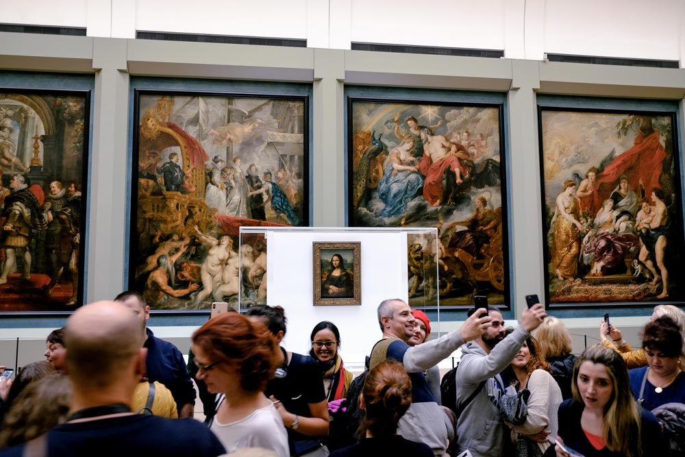 Turistas del Free Tour París en español visitando el el Museo del Louvre frente a la Gioconda