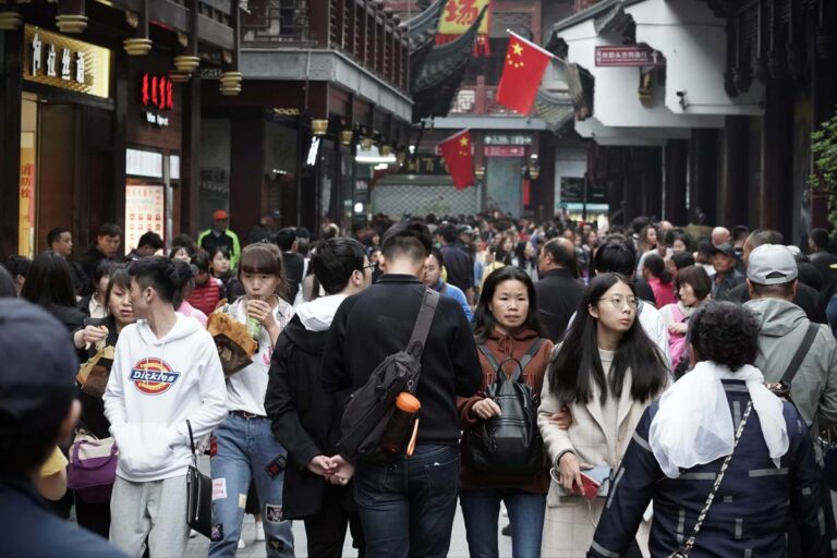 Chinos caminando a lo largo de una concurrida calle comercial en Shanghai (China)