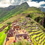 Ruinas incas de Machu Picchu con terrazas escalonadas, visitantes recorriendo el sitio y montañas verdes al fondo